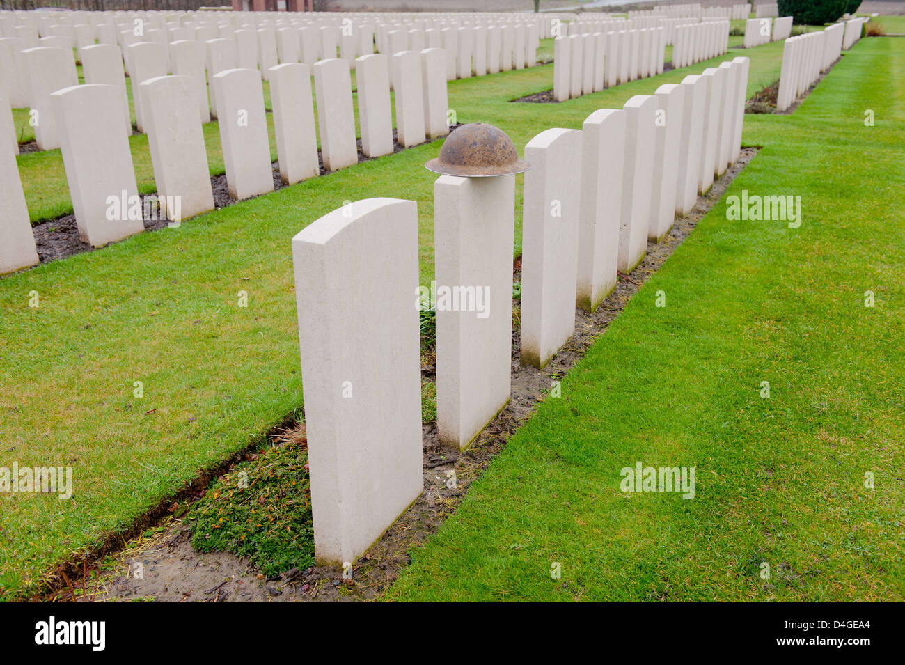 Leere Grabsteine auf einem Commonwealth-Militär-Friedhof in Belgien. Eines der Grabsteine hat einen britischen Helm ruht an der Spitze. Stockfoto