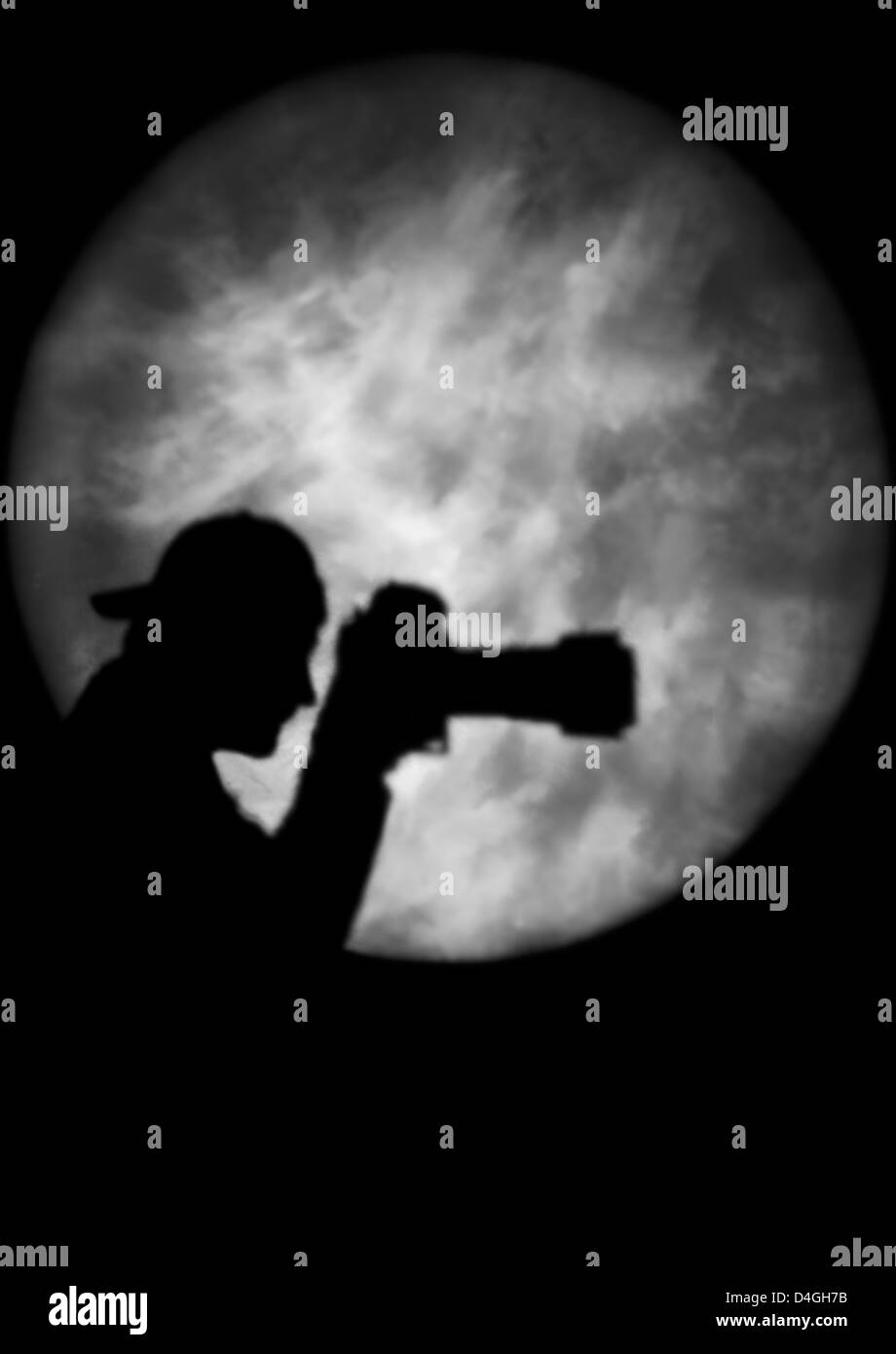 Silhouette eines Mannes hält eine Kamera im Rampenlicht oder Mondlicht (Modell freigegeben) Stockfoto