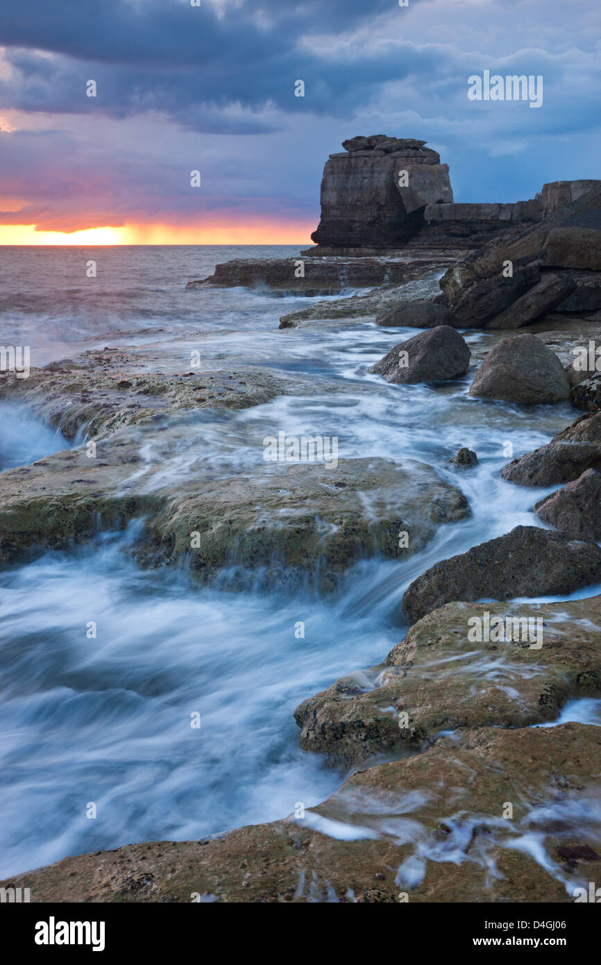 Wellen gegen die felsige Küste der Portland Bill bei Sonnenuntergang. Isle of Portland, Dorset, England. Frühling (April) 2012. Stockfoto