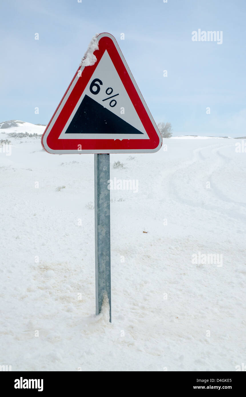 Steile Hügel Warnung Wegweiser in einer verschneiten Straße. Stockfoto