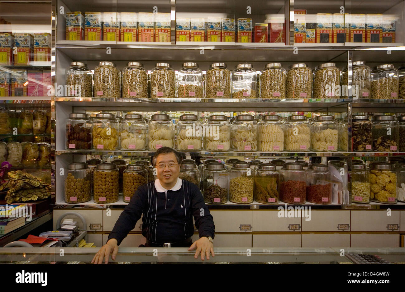Mann hinter dem Tresen ein Lebensmittelgeschäft, Blick in die Kamera, Hong Kong, China Stockfoto