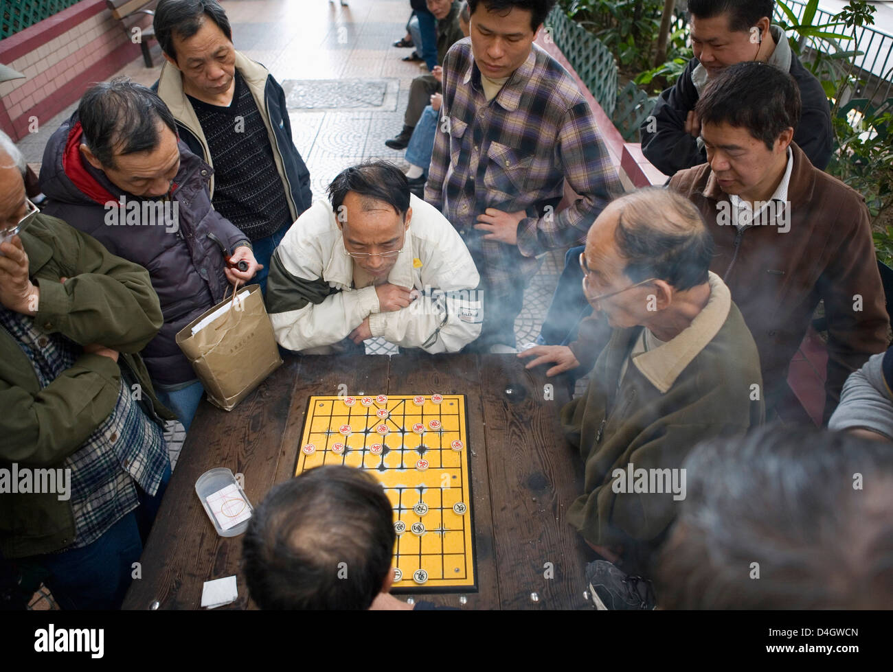 Zwei chinesische Männer spielen chinesisches Schach auf der Straße, andere Männer zusehen, Hong Kong, China Stockfoto