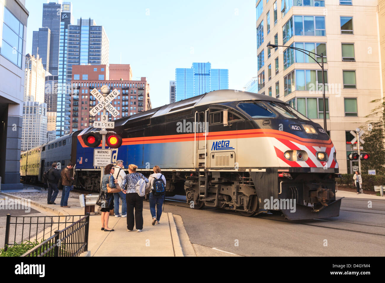 Metra Zug vorbei an Fußgänger an einer offenen Bahnübergang, Downtown, Chicago, Illinois, USA Stockfoto