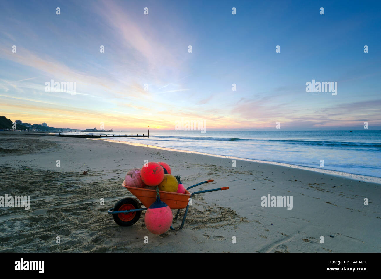 Eine Schubkarre voller Boot Bojen auf Durley Chine Beach mit Bournemouth Pier im Hintergrund. Stockfoto