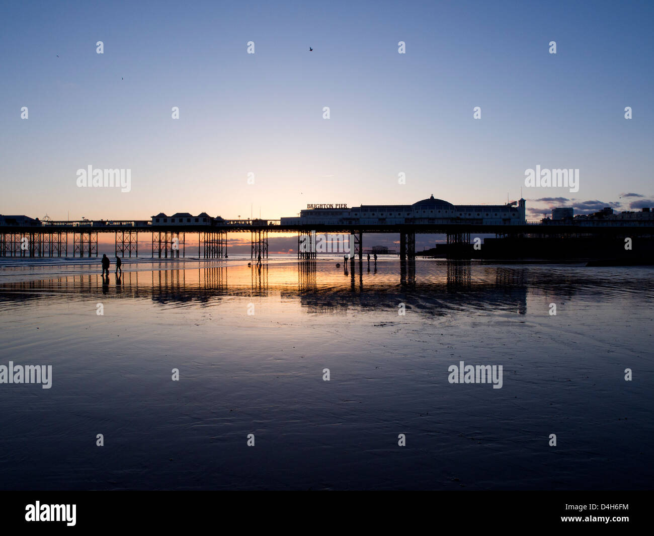 Brighton Pier bei Sonnenuntergang, goldenen Himmel reflektiert den Sand bei Ebbe Stockfoto