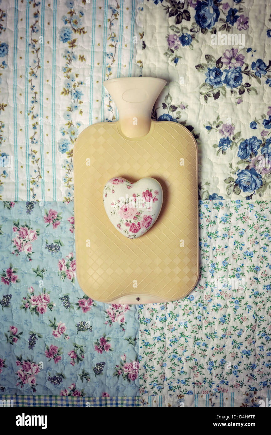 eine Wärmflasche auf einem Vintage Bett mit einem floralen Herzen Stockfoto