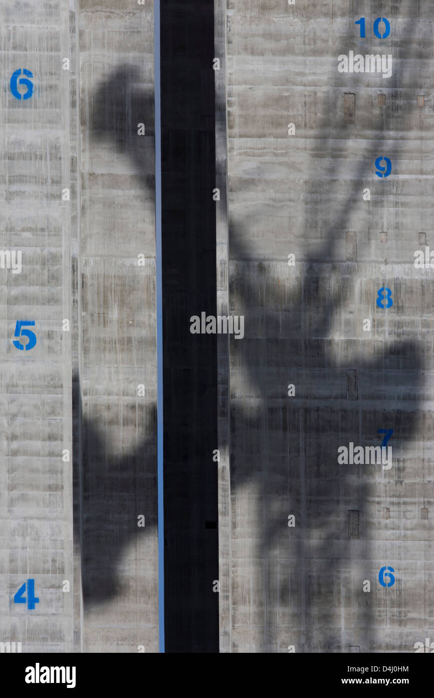 Der Schatten eines Krans ist verteilt sind die Betonoberfläche einem Aufzugsschacht mit ihre Böden vertikal auf 5 Broadgate stellen Architekten, der die neue Heimat der UBS in London bei voller Belegung wird markiert. Gen Himmel erhebt sich turmartiger Baukörper mit blauer Registriernummer der zukünftigen Geschosse, Schablone auf den grauen Stahlbeton. Stockfoto