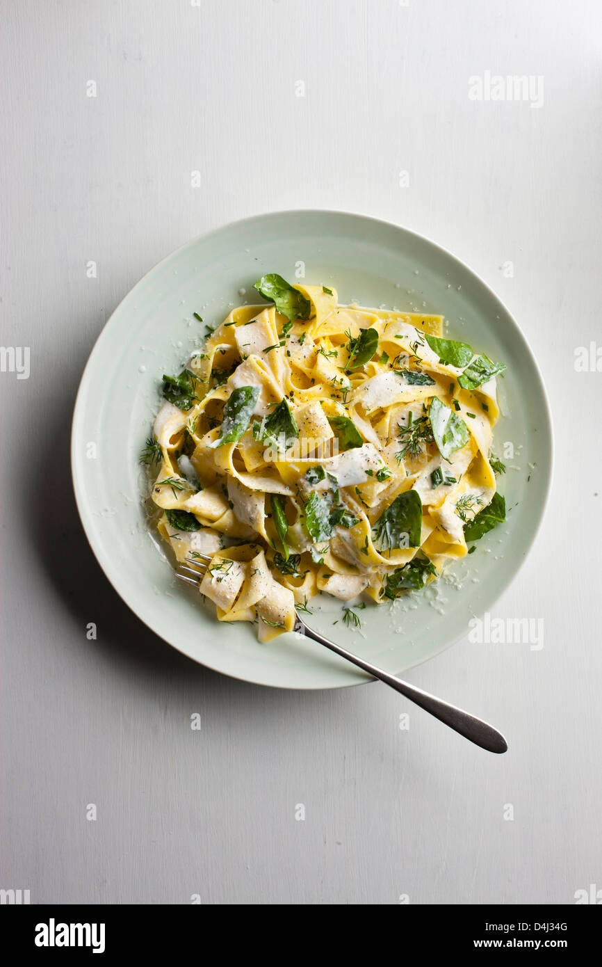 Ein Teller mit Pappardelle Pasta mit cremigem Ricotta, Baby-Spinat, frischen Kräutern und Pfeffer. Stockfoto