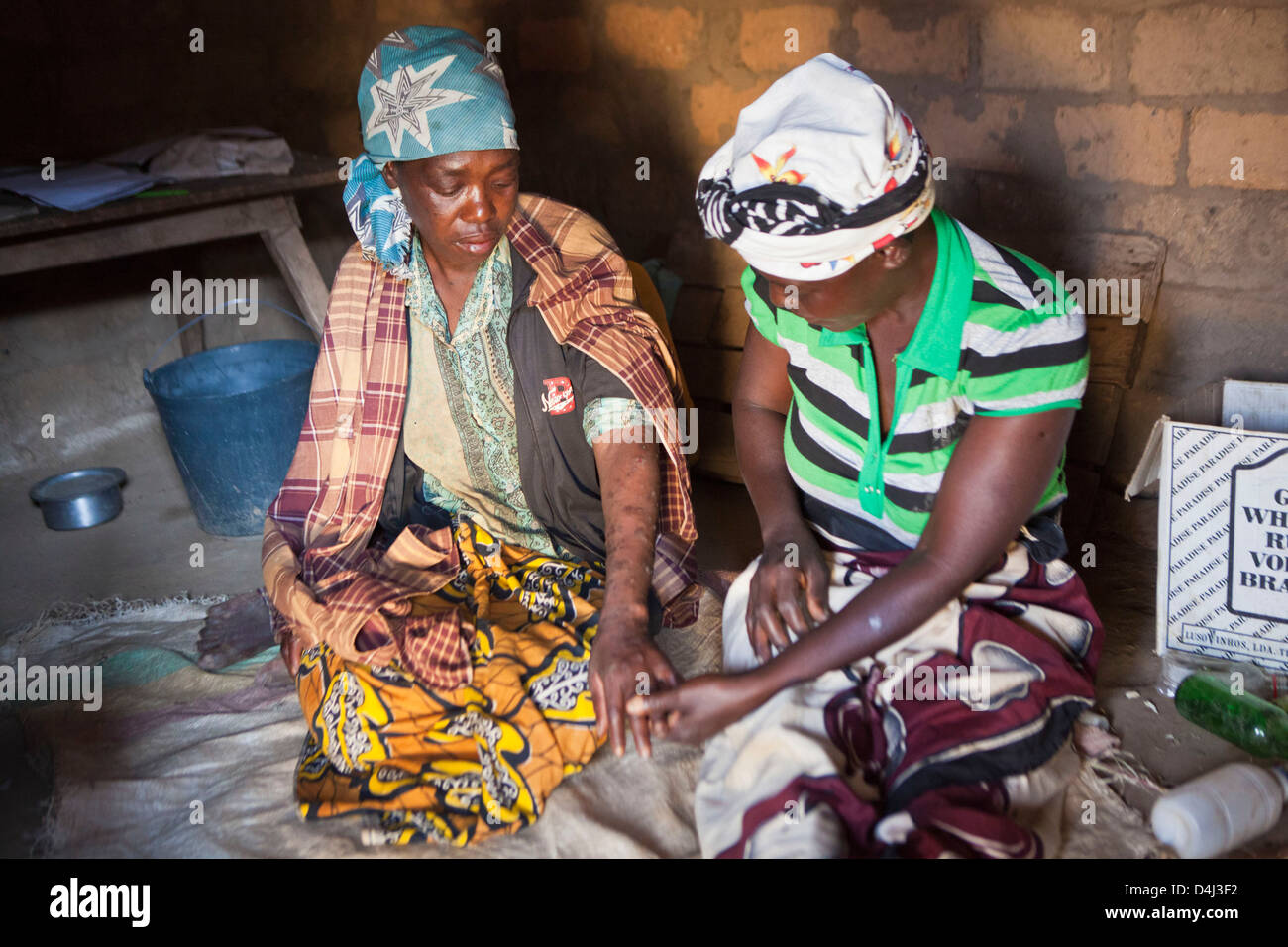 Afrikanische Frau zu Hause in ihrem Dorf, Mosambik. Sie ist in einem schlechten Gesundheitszustand und hat Besuch von einer Pflegekraft zu unterstützen. Stockfoto