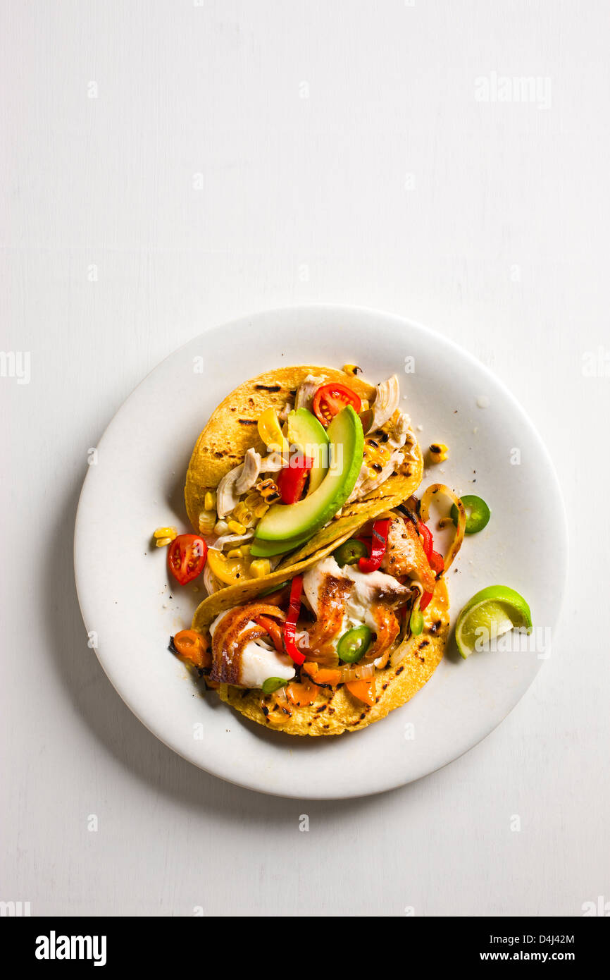 Hühnerfleisch Tacos mit Tomaten, Avocado und gegrilltem Mais + angebraten Tilapia Tacos mit bunten Paprika und gegrillte Zwiebeln. Stockfoto