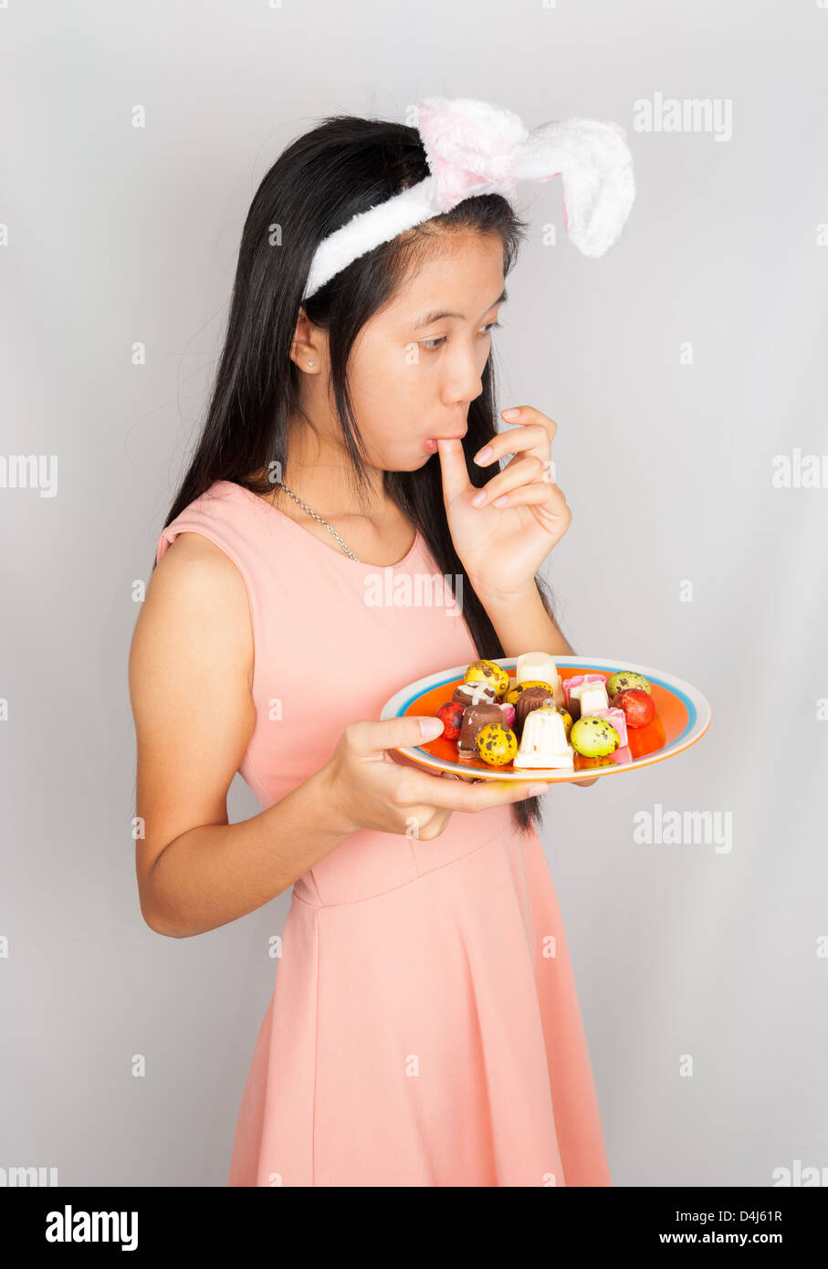 Niedlichen Häschen Asiatin halten Teller Ostereier und Schokolade. Stockfoto