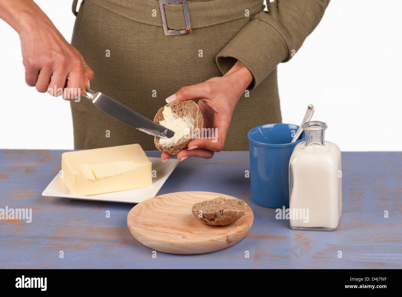 Verbreitung von frischer Butter auf einem Vollkorn-Brötchen Stockfoto