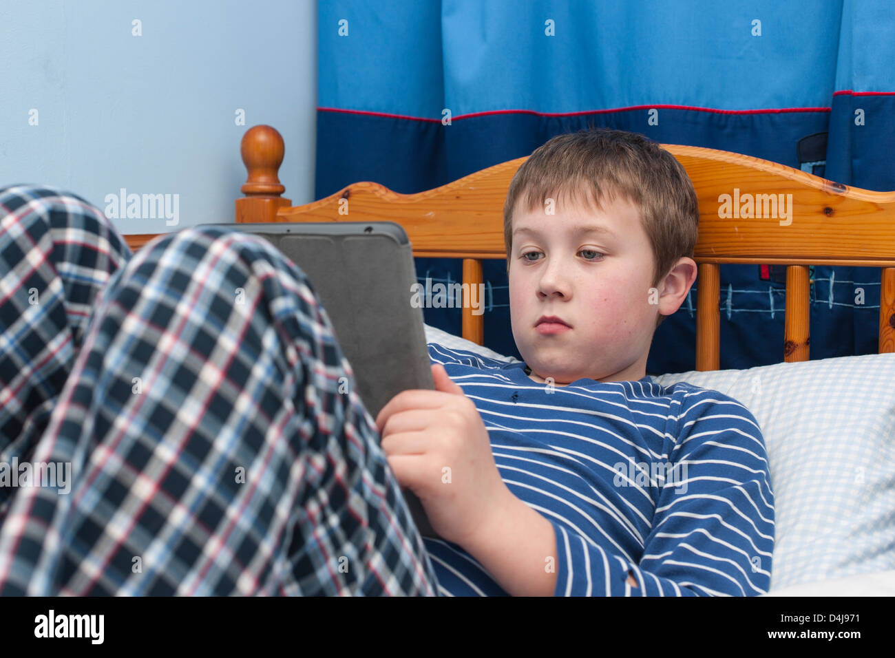 Ein neun Jahre alter Junge mit seinem Ipad Tablet in seinem Schlafzimmer Stockfoto