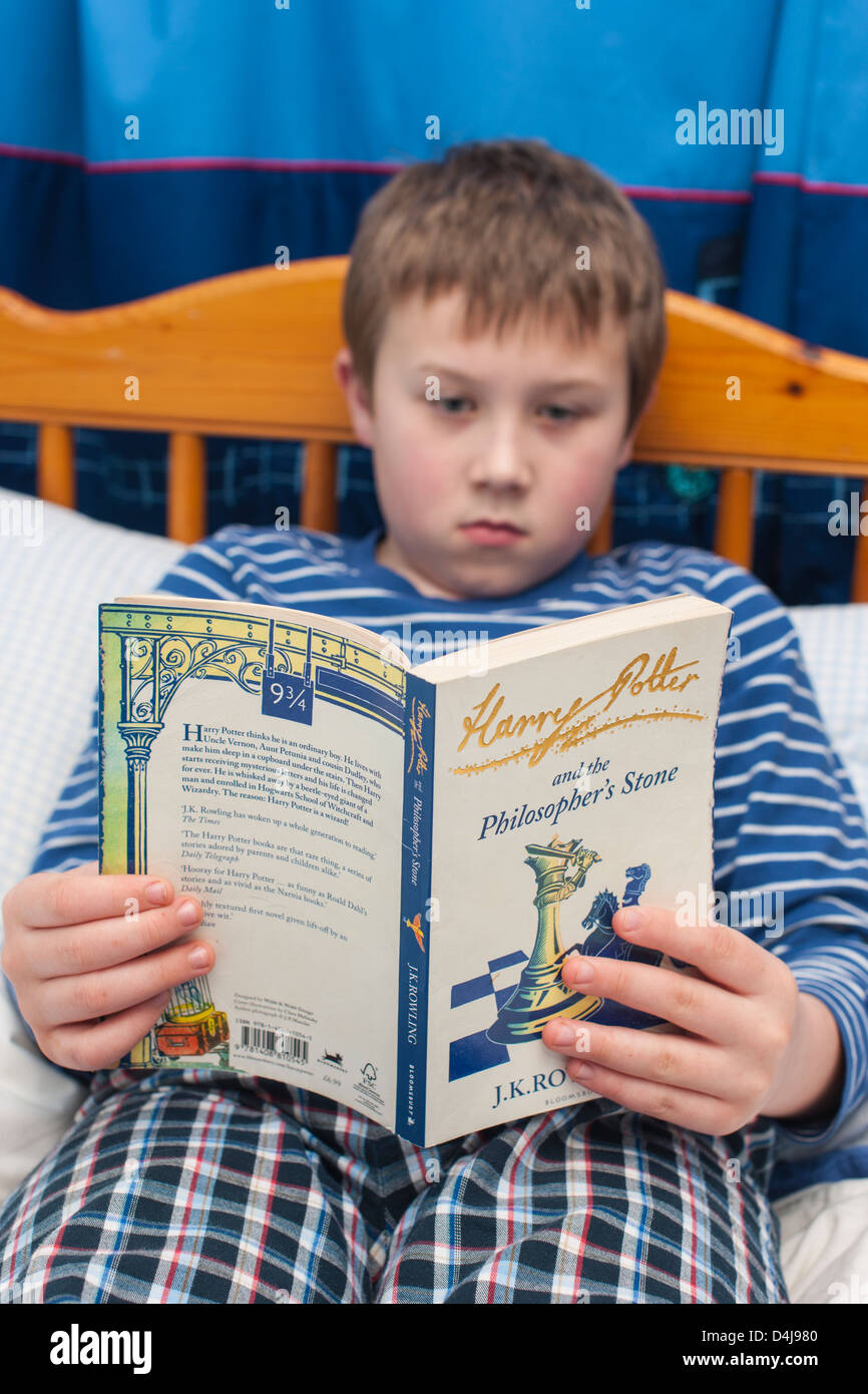 Ein neun Jahre alter Junge liest der Harry-Potter-Kinder in seinem Schlafzimmer buchen Stockfoto