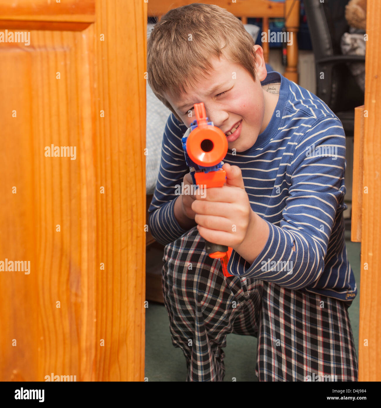 Ein neun Jahre alter Junge mit einem Nerf Gewehr in seinem Schlafzimmer Stockfoto