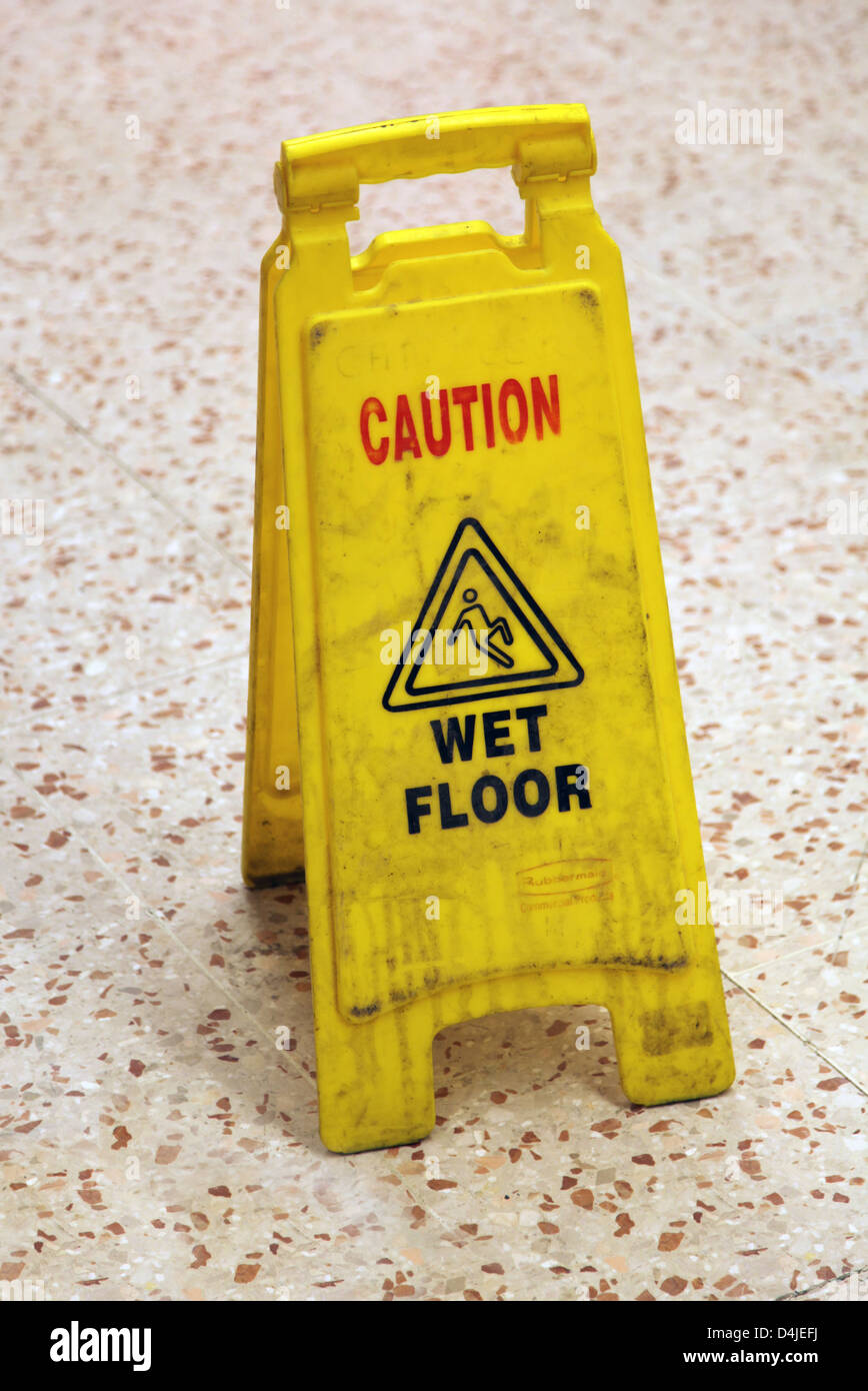 Es ist ein Foto von einem Achtung-Schild, das auf dem Boden in einem Korridor stehen. Es besteht aus gelben Kunststoff und nassen Boden sagen Stockfoto