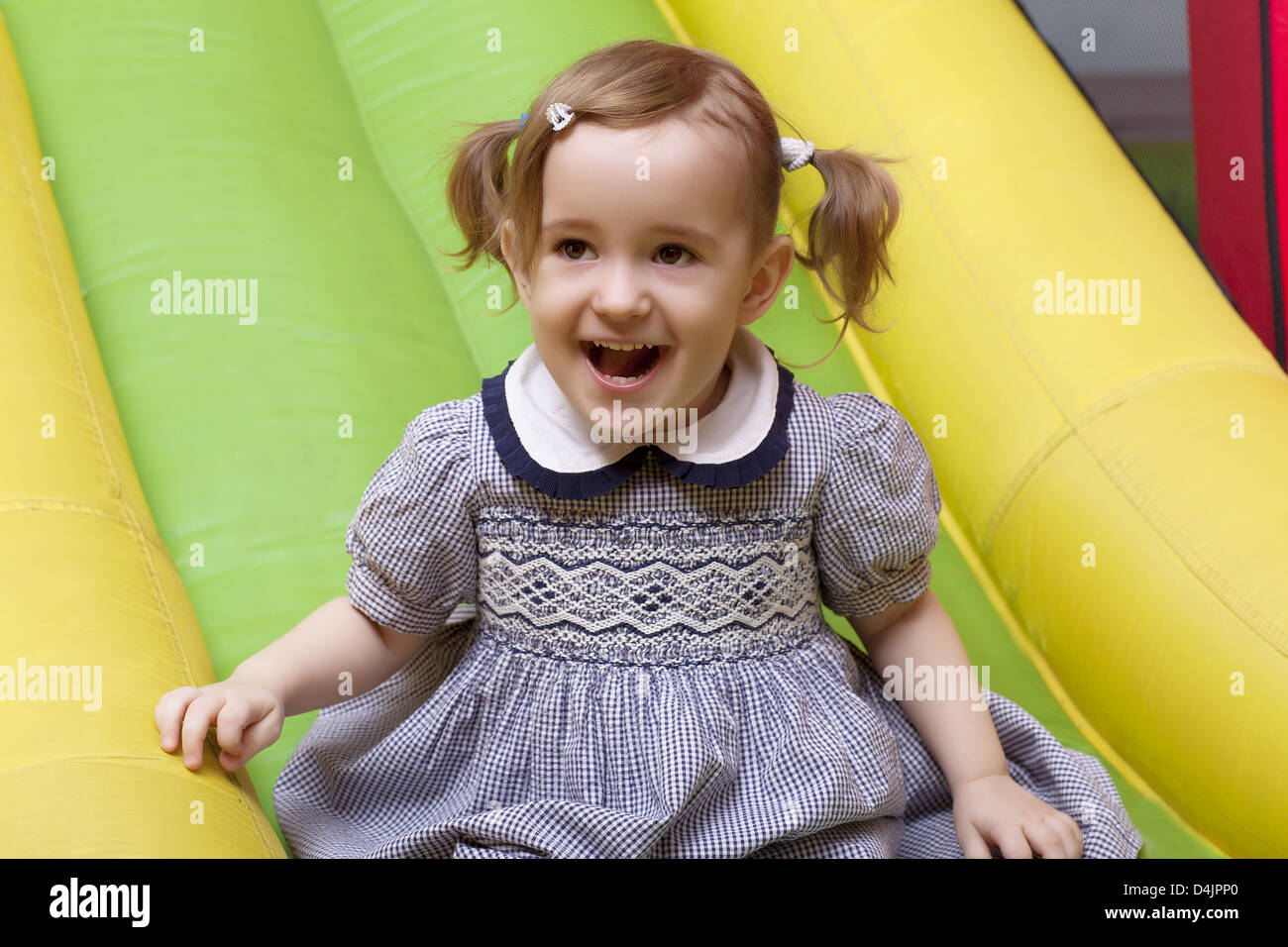kleines Mädchen auf Spielplatz Folie lacht Stockfoto