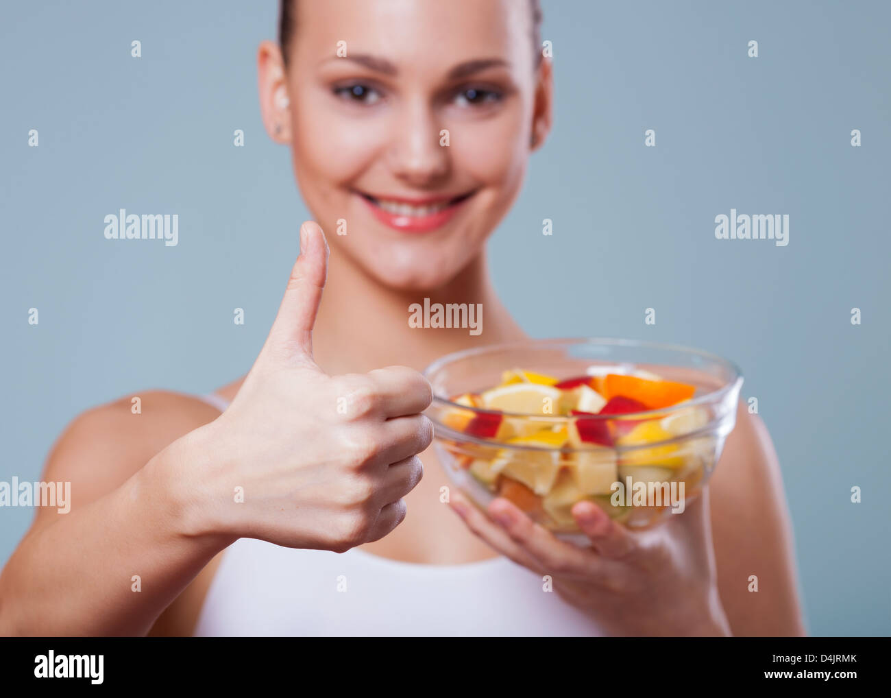 Porträt von einem schönen Mädchen hält eine Schale mit Obst, Salat und geben ein "den Daumen nach oben" an die Kamera mit Ihrem Stockfoto