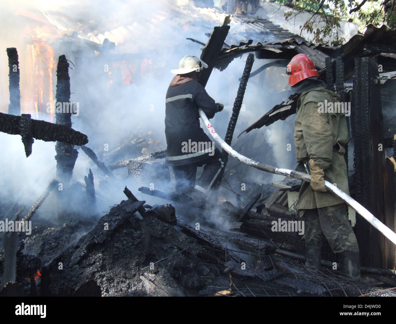 Schwelende Reste eines Ghetto-Hauses mit sprühen Wasser Feuerwehr Feuerwehrmann löschen ein Feuer in einem Mehrfamilienhaus Stockfoto