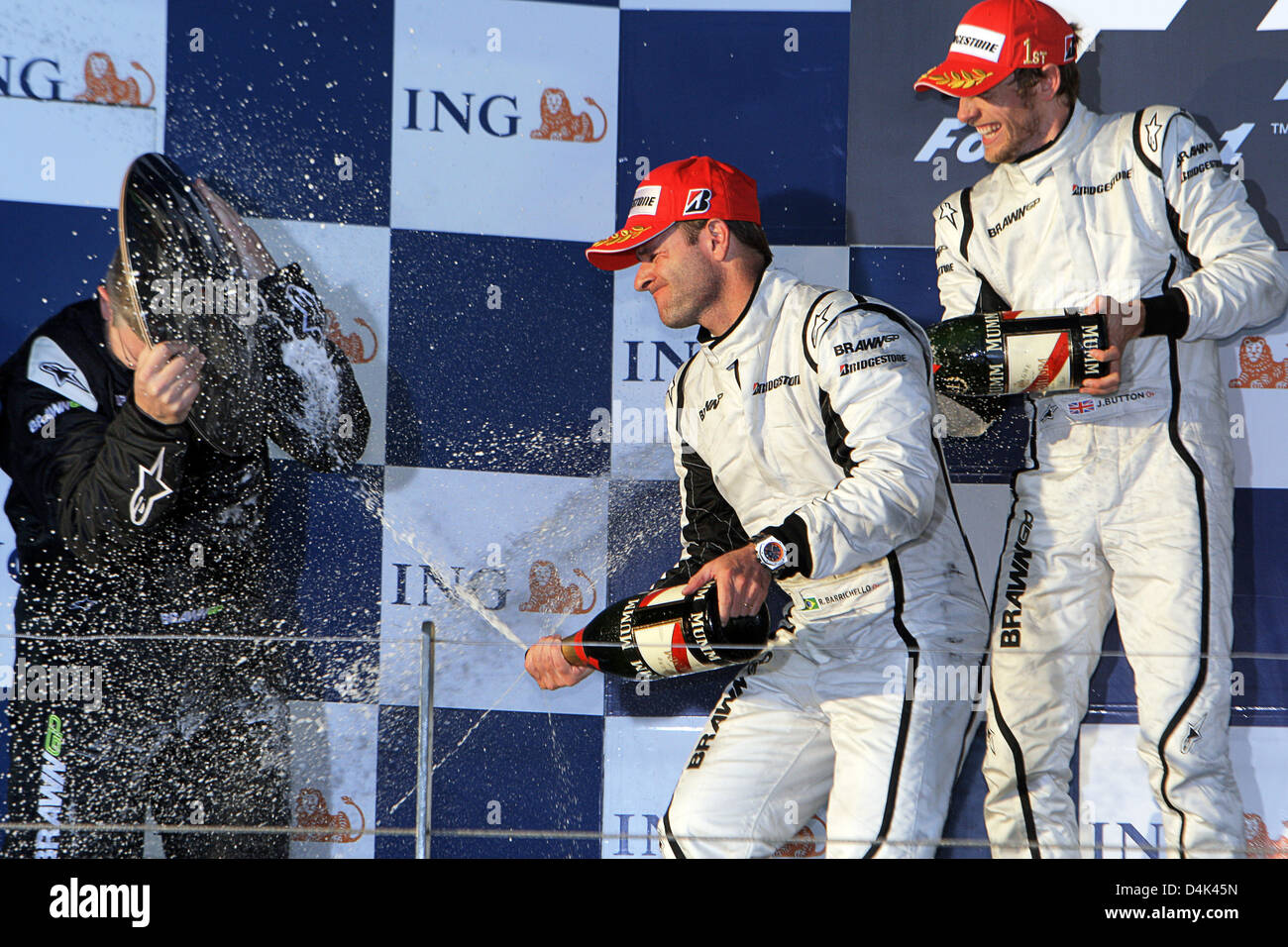 Britische Formel1-Fahrer Jenson Button (R) von Brawn GP und brasilianischer Teamkollege Rubens Barrichello (C) feiern nach dem Gewinn der ersten und zweiten Platz in der australischen Formel Eins Grand Prix im Albert Park Circuit in Melbourne, 29. März 2009 mit Brawn GP Besitzer Ross Brawn (L) auf dem Podium. Schaltfläche "fertig" folgten zunächst seinem brasilianischen Teamkollegen Barrichello und italienische Formel Stockfoto