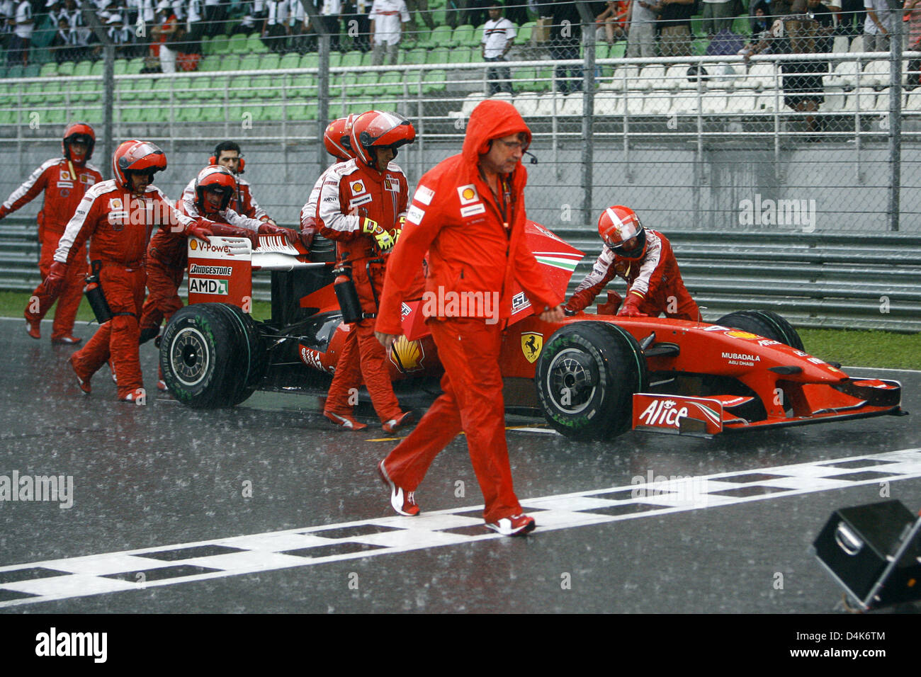 Scuderia Ferrari Mechanik stehen auf der Rennstrecke, wie der Grand Prix von Malaysia durch Starkregen auf Sepang außerhalb Kuala Lumpur, Malaysia, 5. April 2009 unterbrochen wurde. Foto: JENS Büttner Stockfoto