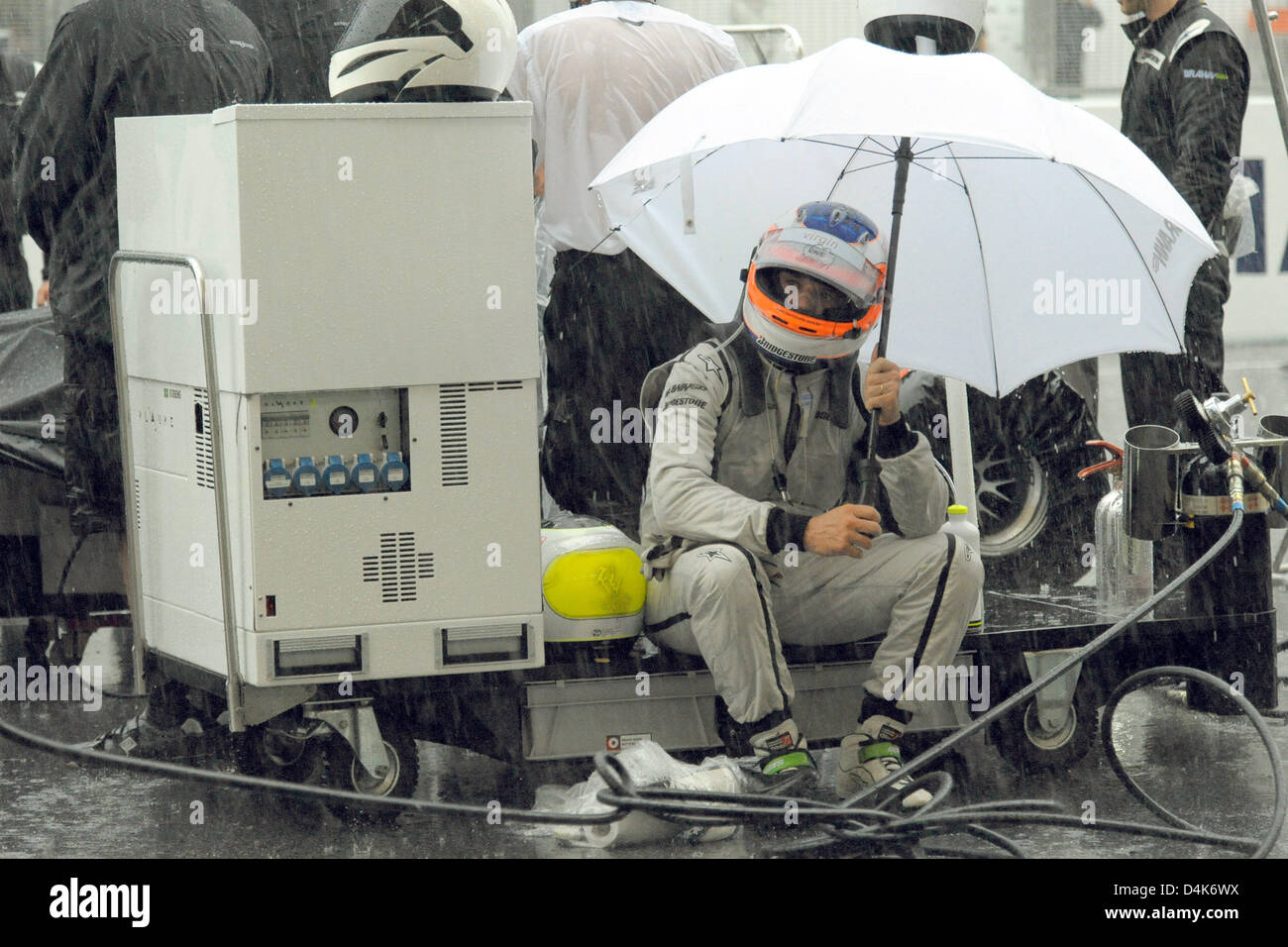 Brasilianische Formel-1-Pilot Rubens Barrichello von Brawn GP sitzt unter einem Regenschirm während des Grand Prix von Malaysia in Sepang Circuit außerhalb Kuala Lumpur, Malaysia, 5. April 2009. Das Rennen war nach 31 Runden wegen Starkregen rot gekennzeichnet. Foto: Peter Steffen Stockfoto
