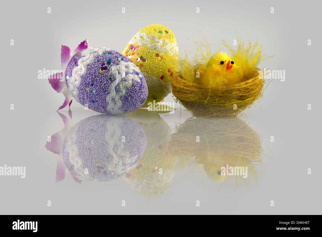 Ostern-Küken im Nest und zwei Eiern dekoriert in einem grauen Hintergrund Stockfoto