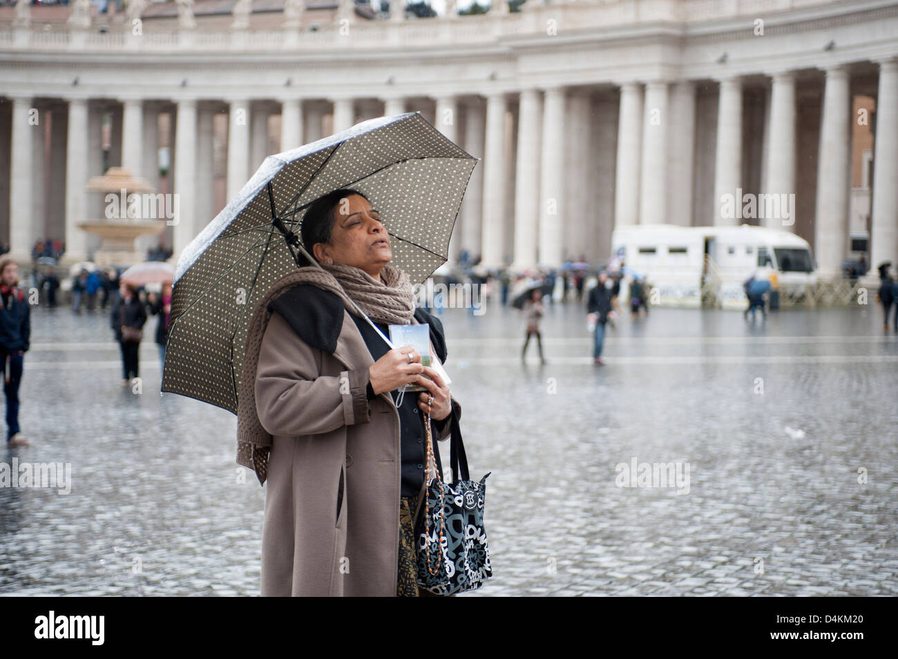 Frau mit Regenschirm betet in dem Petersplatz Stockfoto