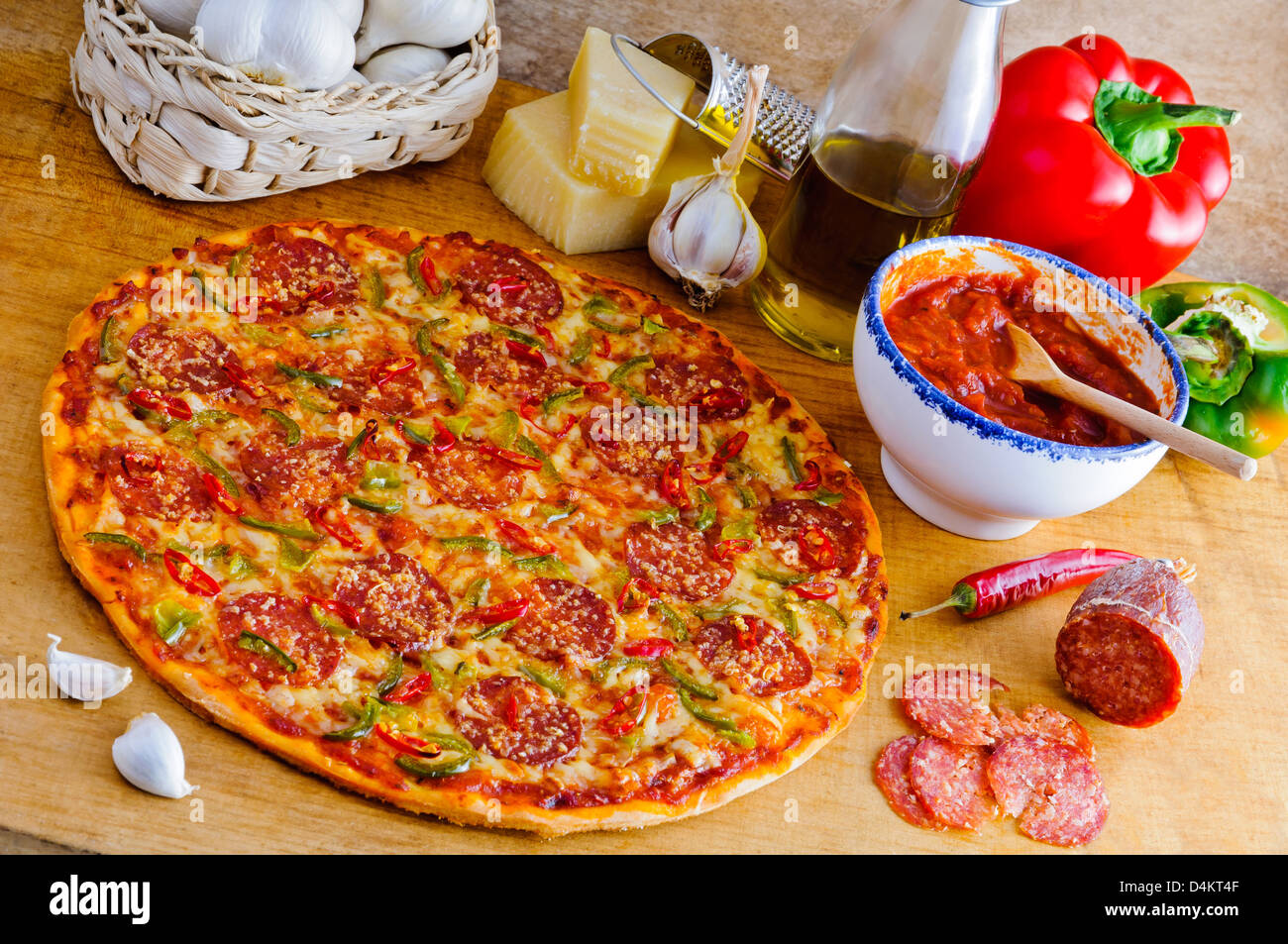 Traditionelle italienische Peperoni-Pizza und Zutaten auf einem Holztisch Stockfoto