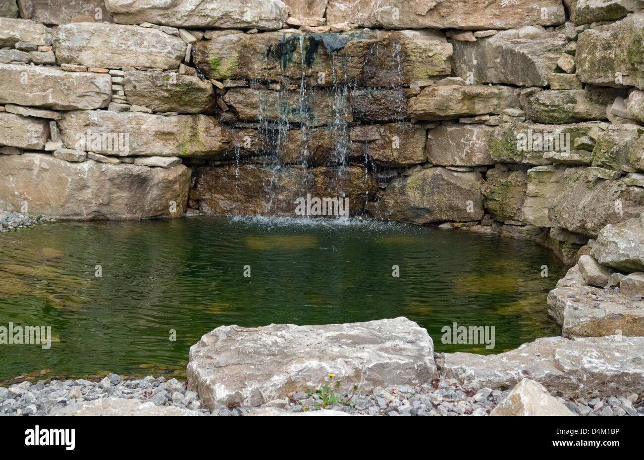 kleiner Teich, umgeben von einer Steinmauer mit fließendem Wasser Stockfoto