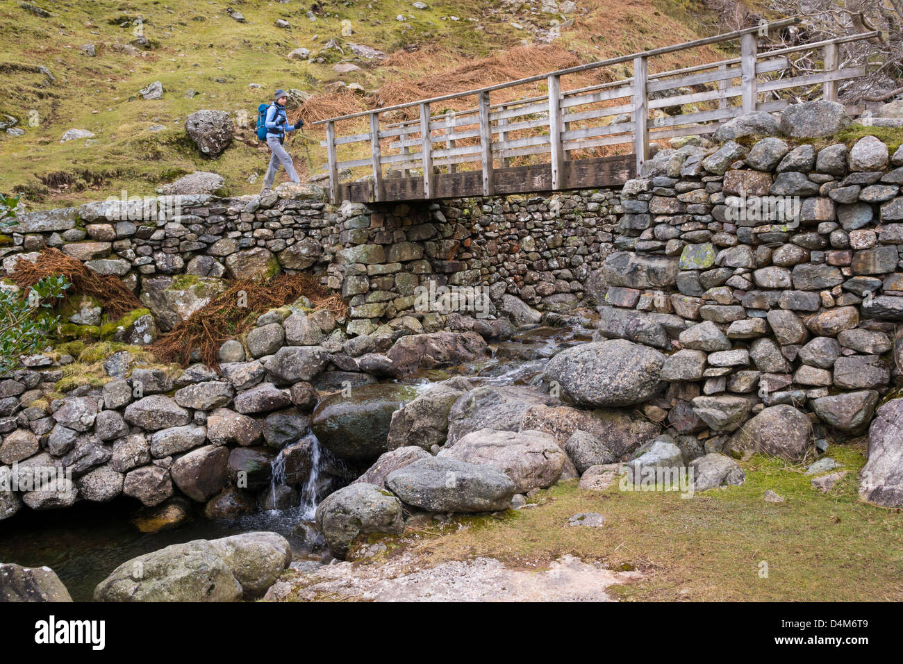 Ein Wanderer scheut Ghyll im Lake District eine Holzbrücke überqueren. Stockfoto