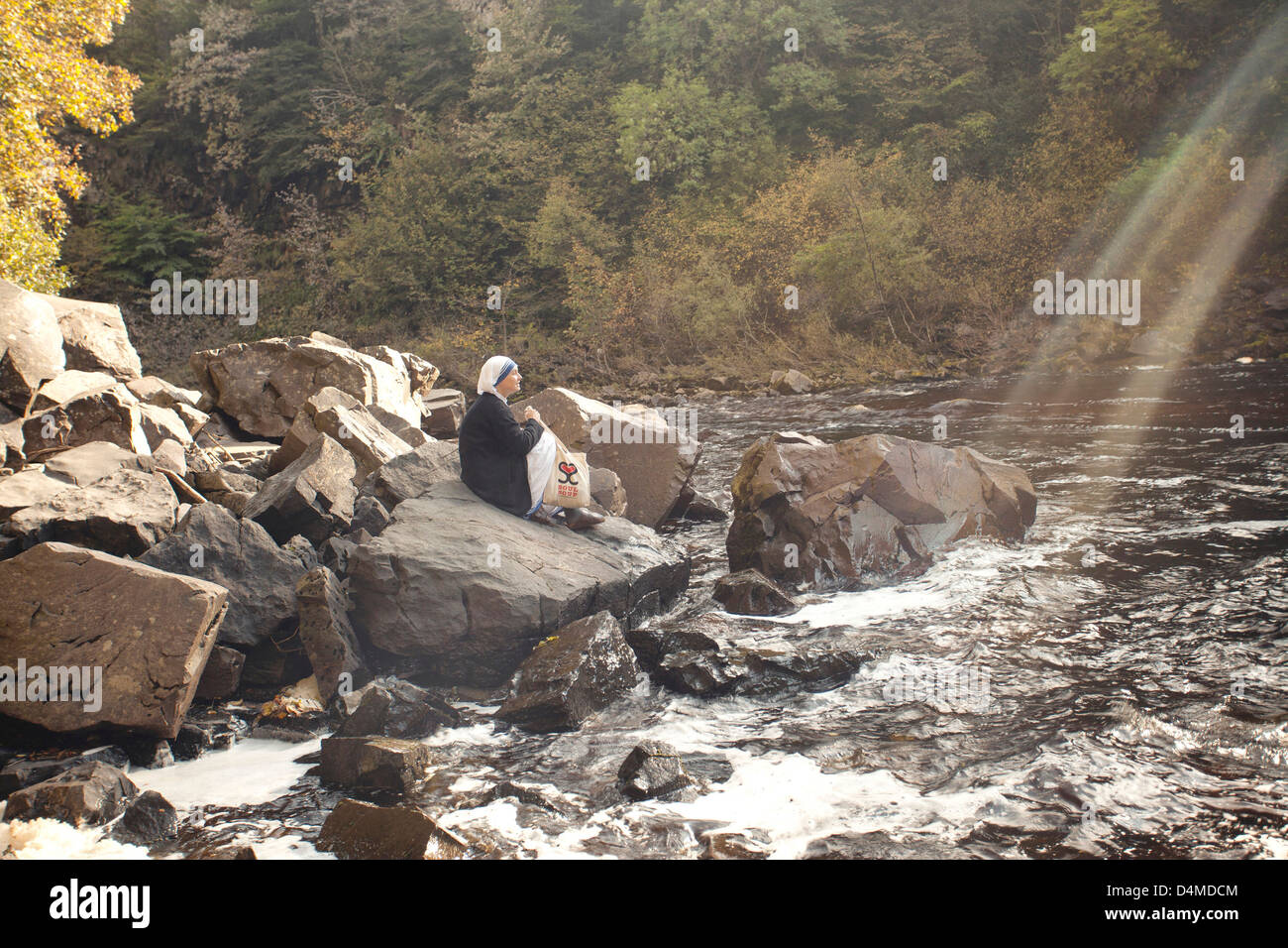 Ich sah die Nonne hingerissen von den Wasserfällen, die Welle des Sonnenlichts erschien pünktlich wie von Nachfrage. Stockfoto