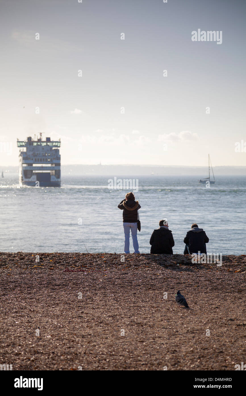 Menschen am Strand von Southsea in Portsmouth mit Blick zu einem Wightlink Auto Fähre in der Solent Überschrift nach Fishbourne, Isle Of Wight Stockfoto