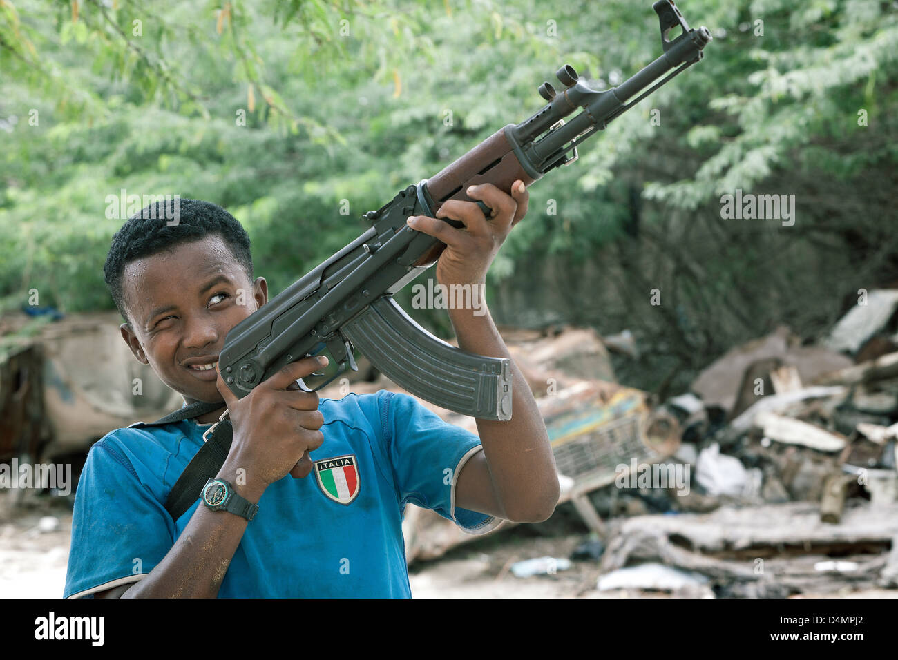 Ein somalischer junge hält ein AK-47 Sturmgewehr und Durchsicht der Entfernungsmesser an vorderster Front. Stockfoto