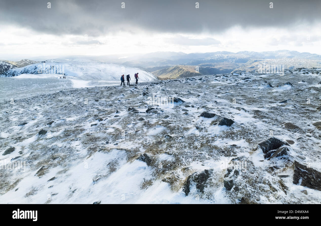 Drei Wanderer über den Gipfel des Lakelandpoeten im Winter mit Nethermost und Dollywagon in der Ferne. Stockfoto