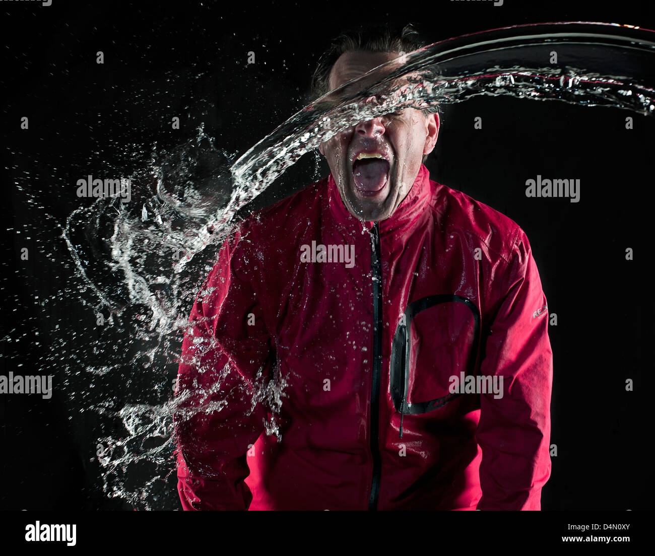 Mann in rote Regenjacke mit Wasser bespritzt werden Stockfoto