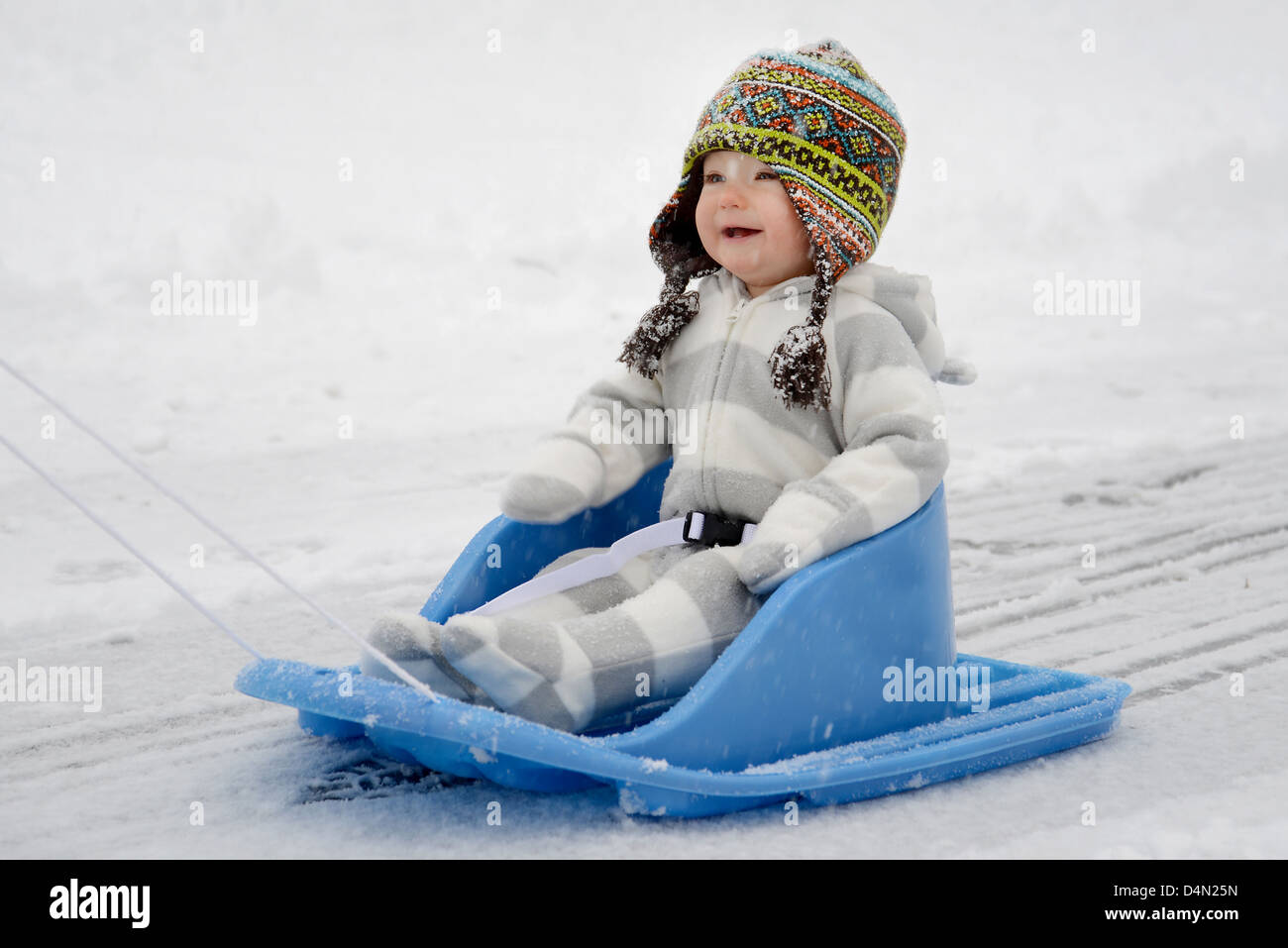 Baby Hut genießen den Winterschnee beim Rodeln Stockfoto
