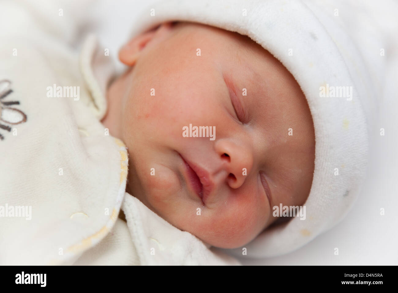 Neugeborene schlafen Babymädchen gehüllt in ein Vlies Body und Hut. In genau 2 Stunden alt genommen. Auge im Mittelpunkt. Stockfoto