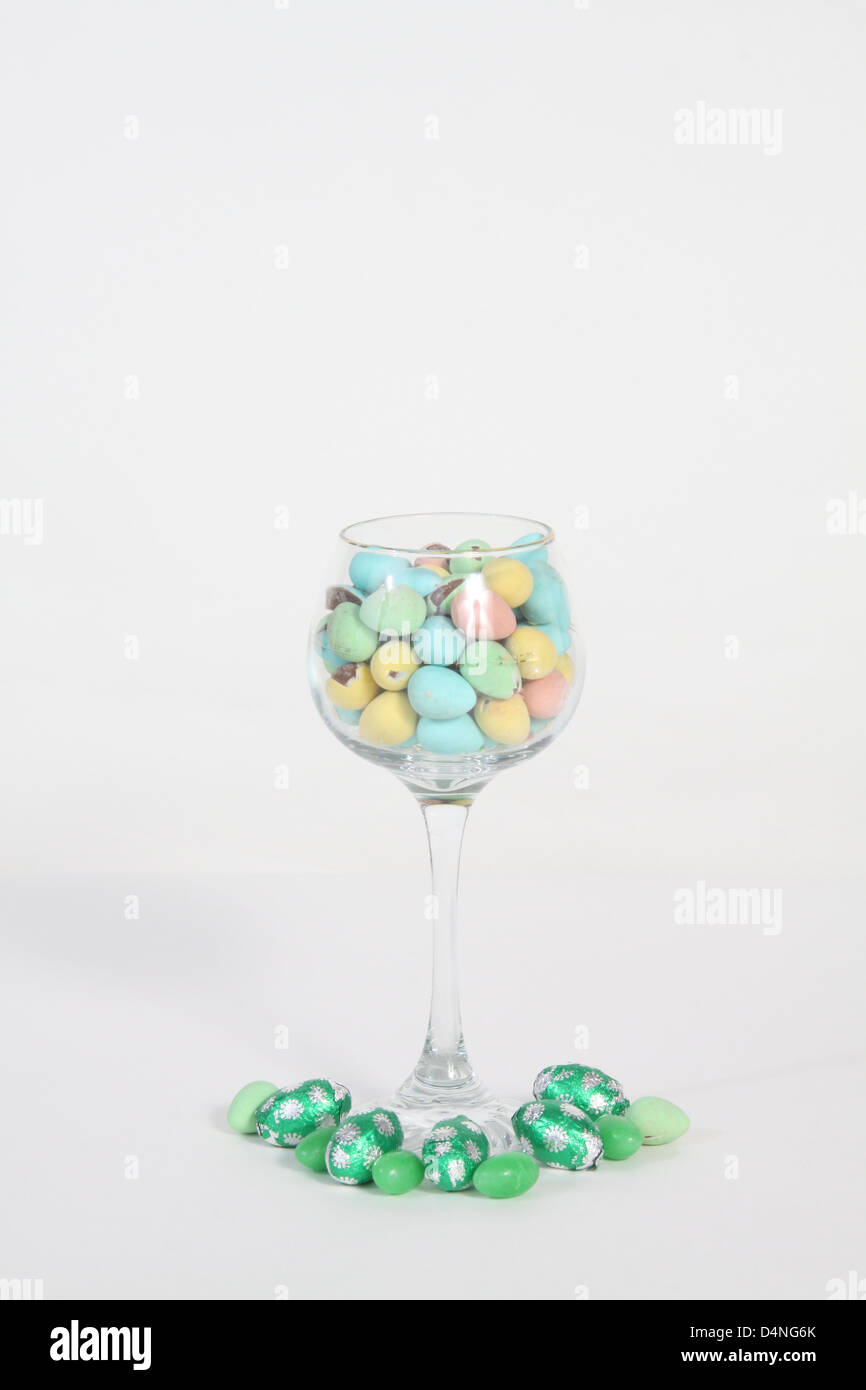 Glas Wein gefüllt mit Bonbons in verschiedenen Farben Stockfoto