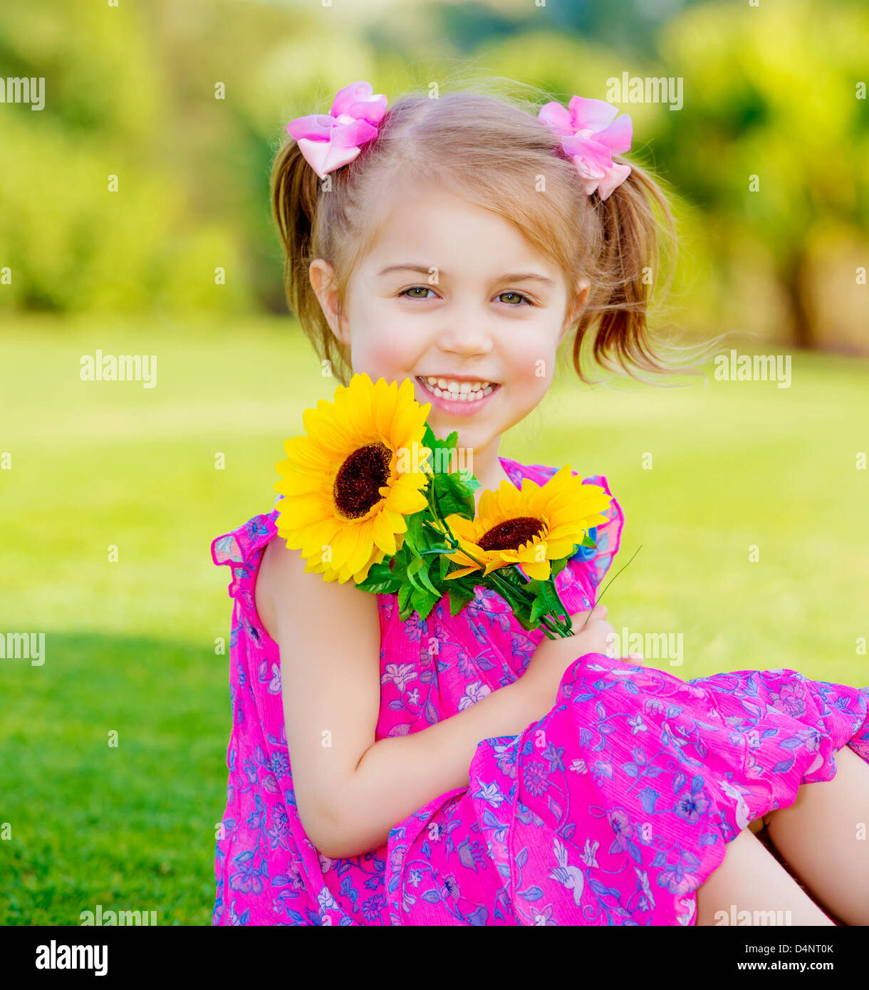 Glückliches Babymädchen spielen im Freien, niedlichen Kind hält frische Sonnenblume Blumen Kind Spaß im Sommerpark, schöne Kleinkind Stockfoto