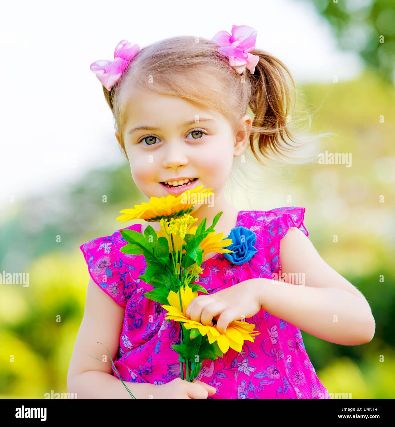 Glückliches Babymädchen spielen im Freien, niedlichen Kind hält frische Sonnenblume Blumen Kind Spaß im Sommerpark Stockfoto