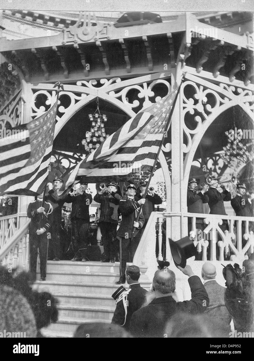 John Philip Sousa Band spielen am Musikpavillon während zwei Bandmitglieder auf Treppe stehen, winken amerikanische Flaggen - Paris Weltausstellung 1900 Stockfoto