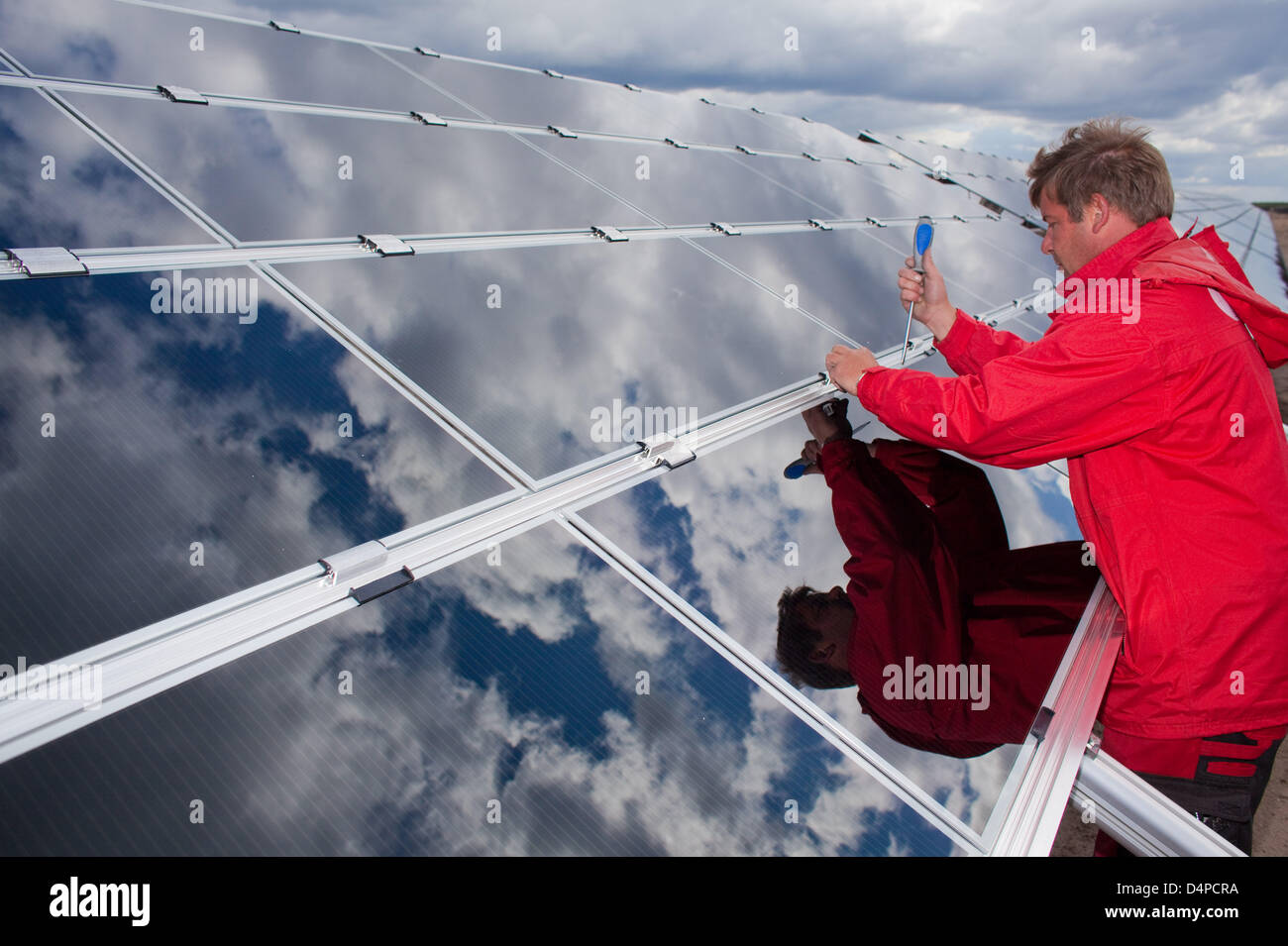 Ein Mann arbeitet auf Dünnschicht-Solarmodule auf dem ehemaligen Truppenübungsplatz Lieberose in der Nähe von Cottbus, Deutschland, 5. Juni 2009. Hier die Firma? Juwi Solar GmbH? baut eine riesige photovoltaische-Anlage bestehend aus Dünnschicht-Module auf einer Fläche von 162 Hektar. Nach Angaben des Unternehmens ist die Leistung von 53 Megawatt dem System der zweitgrößte in der Welt und die größte in Deutschland. Die Stockfoto