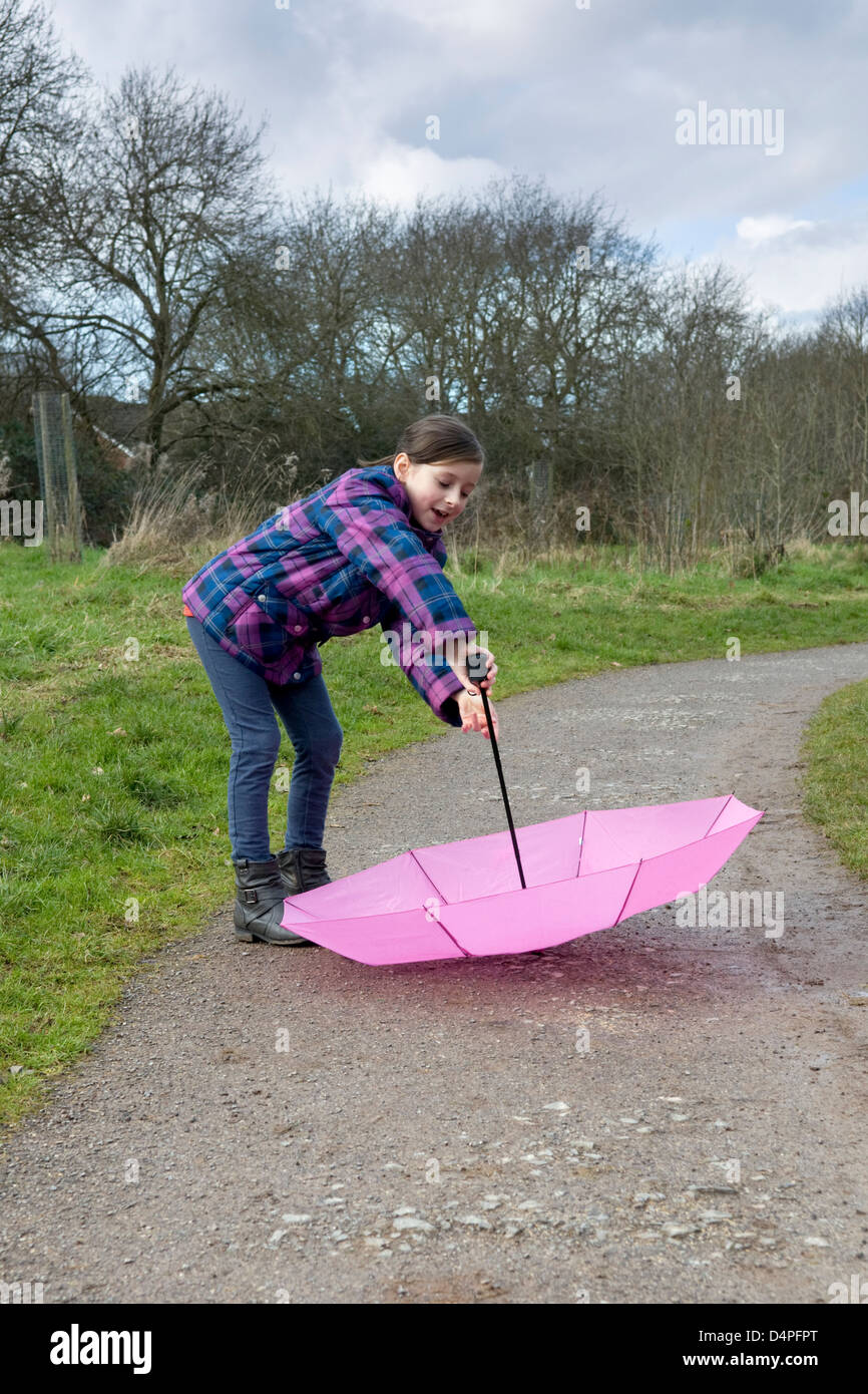 8 Jahre alte kaukasische Mädchen mit rosa Regenschirm im park Stockfoto