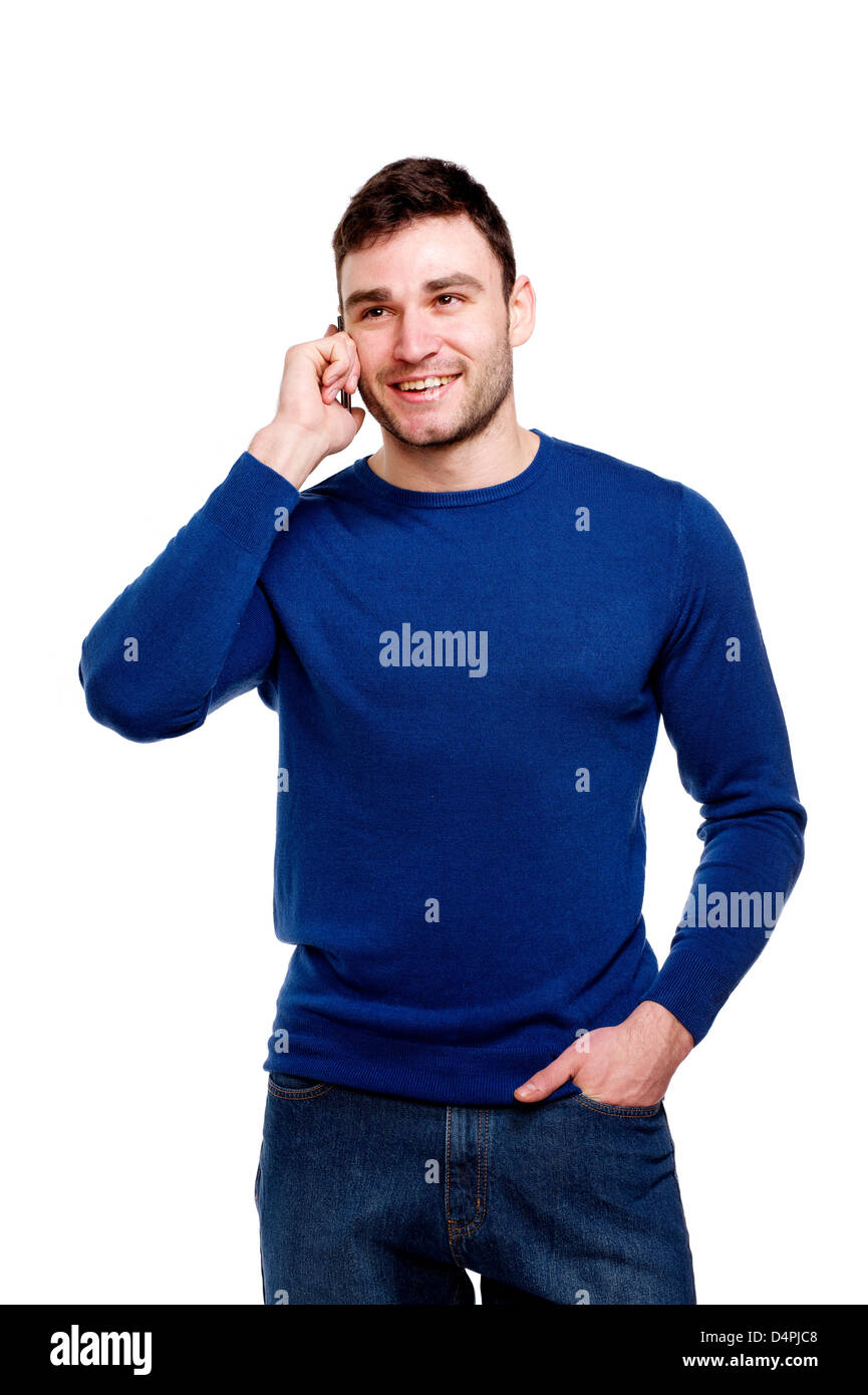 Attraktive junge Mann trägt einen blauen Pullover und Jeans Stand telefonieren mit einem Handy isoliert auf weißem Hintergrund Stockfoto