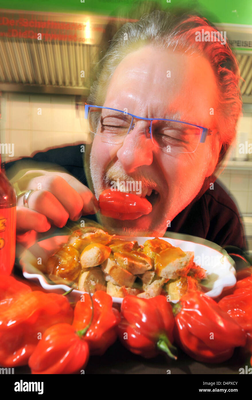 Gerd Herzog beißt in eine Habanero-Chili-Schote in seinem Imbiss in Herne, Deutschland, 7. September 2009. Der Gastronom? s zehn Stufen der Schärfe standhaft Chili-Experten an ihre Grenzen bringen. Herzog? s Saucen sind hausgemacht und, wie er sagt, er ist in der Lage, die Welt zu produzieren? s heißesten Currywurst. Im Gegensatz zu vielen anderen Imbissbuden besitzt er die angeblich heißeste Würze, die gefunden werden können Stockfoto