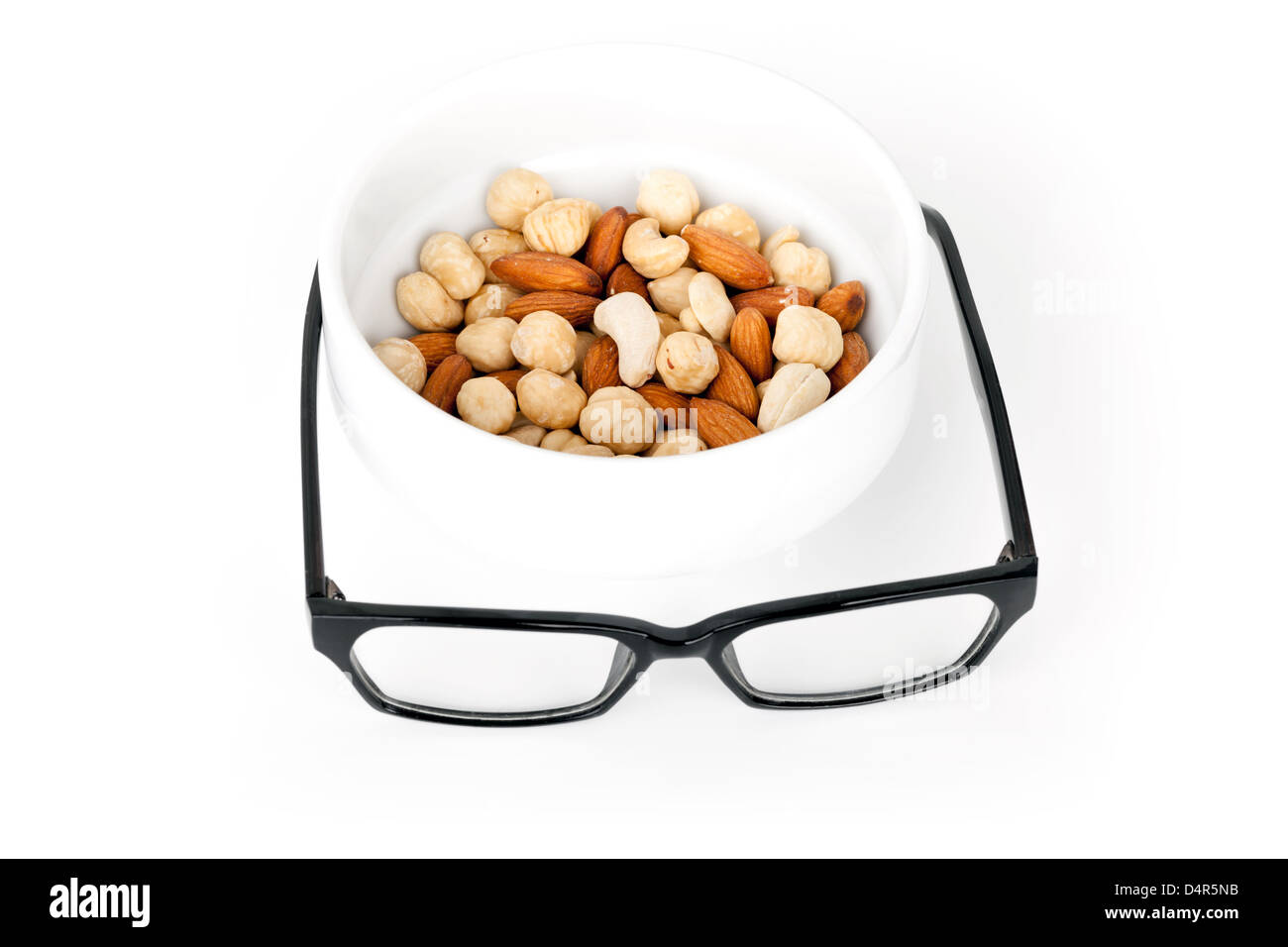 Mentale Einheitsbrei Konzept. Nussmischung im weißen Topf mit schwarzen Brille als Nahrung für Gehirn Stockfoto