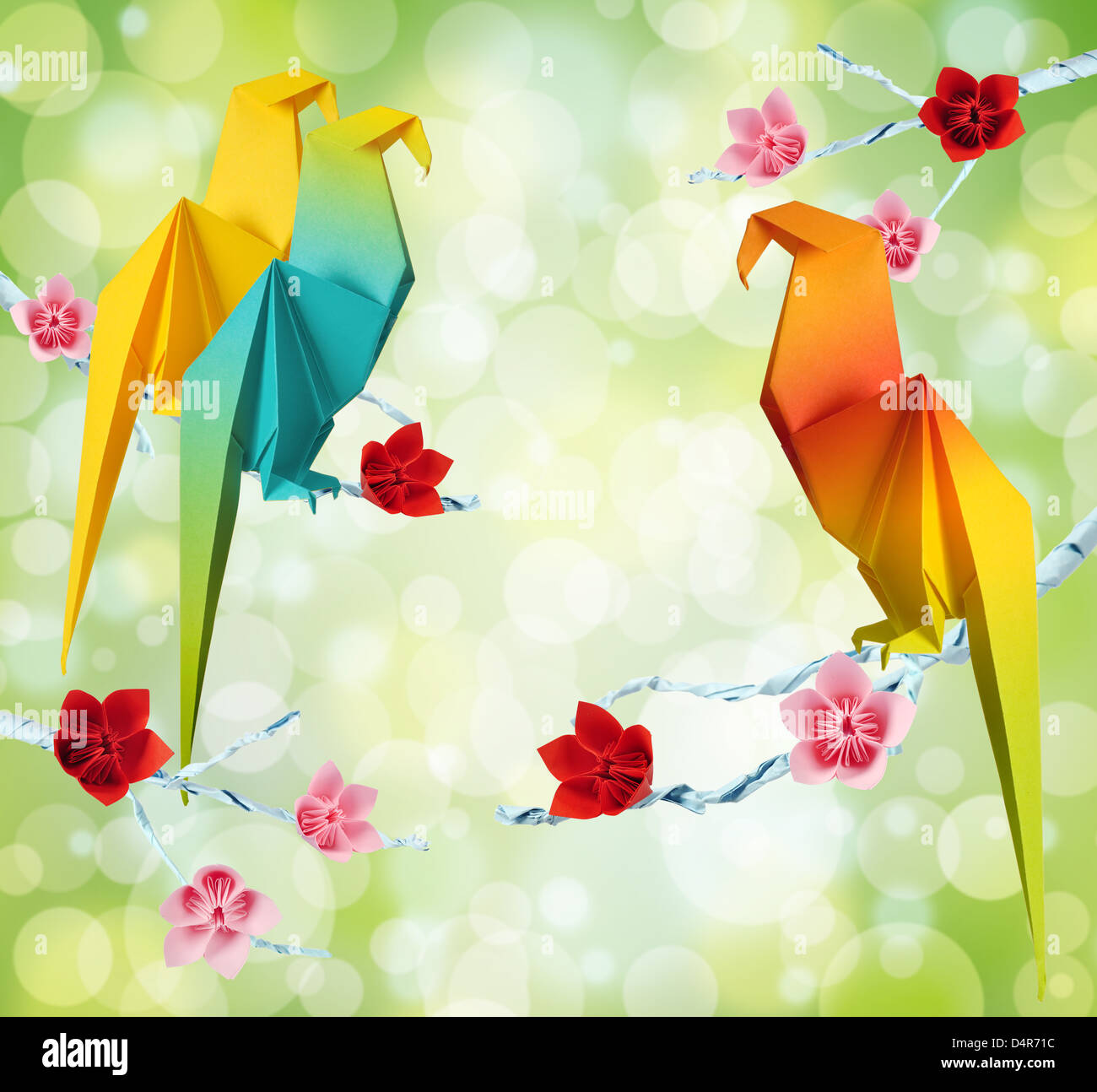 Origami-Papageien auf eine Äste von Bäumen mit Blumen auf grünem Hintergrund Stockfoto