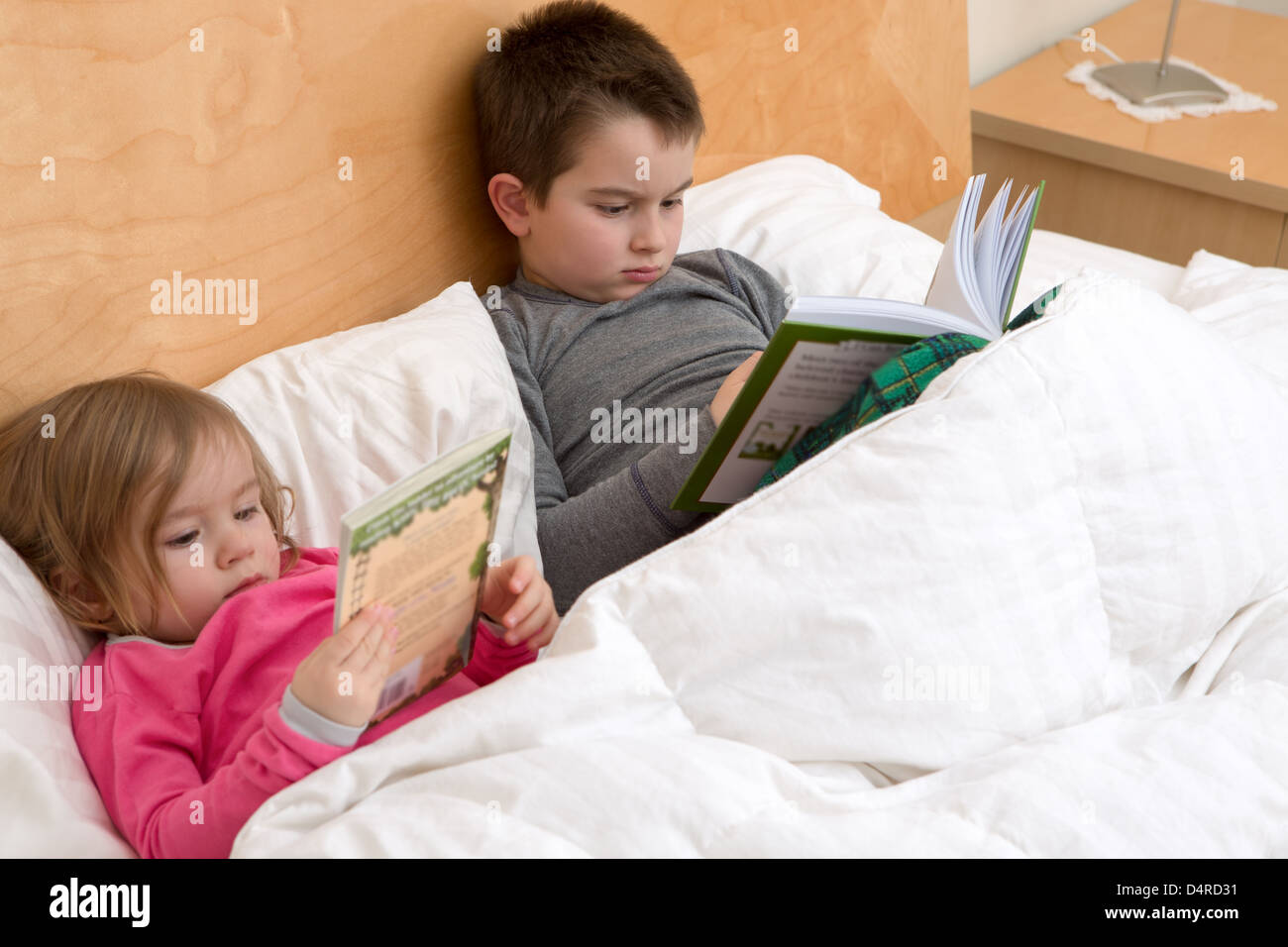 Lesegewohnheiten beginnt mit frühen Alter; Geschwister sind ihre Bücher vor dem Einschlafen lesen. Vielleicht gerade niedlich Kleinkind Stockfoto