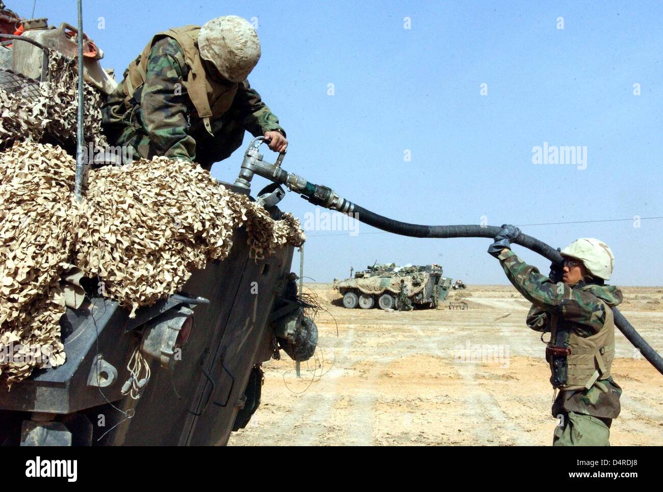 Zwei US-Soldaten des 3. Light Armored Reconnaissance Bataillons der US-Marine Infanterie tanken eine leichte Spähwagen auf Autobahn 1, 90 km südlich von Bagdad, am 1. April 2003. Stockfoto